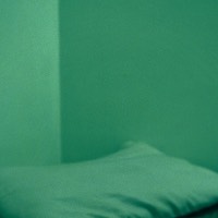 Green tinted image of unmade bed